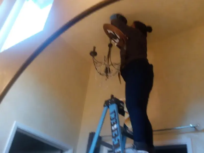 Electrician installing a chandelier in a Lancaster residence